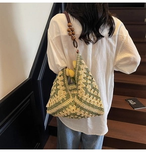 Detail of crochet tote bag with green floral patterns and dark wooden bead shoulder strap