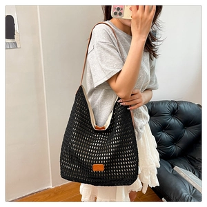 Detailed shot of black mesh woven tote bag featuring brown leather shoulder straps