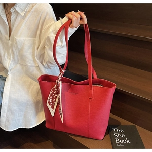 Detail of red litchi texture tote bag with elegant heart pattern silk scarf on handle