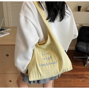 Detail of light yellow pleated tote bag with Live laugh love and bread embroidery