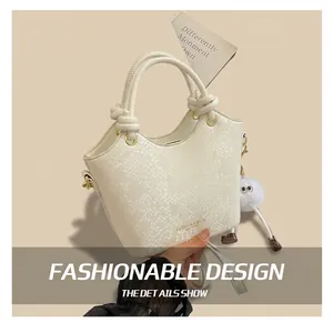 Détail du sac seau blanc texture serpent avec poignée torsadée et ferrures dorées