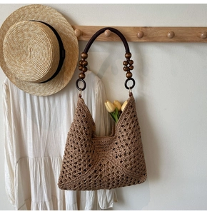 Detail of woven straw tote bag with brown wooden beads and bohemian crochet pattern