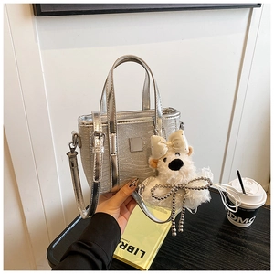 Detail of silver glitter bucket bag with plush bear charm and metallic branding plate