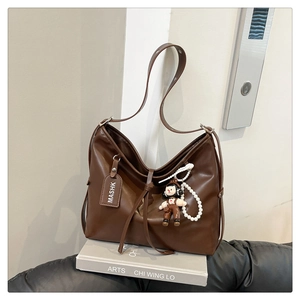 Detail of dark brown matte leather tote with adjustable strap and cute doll charm