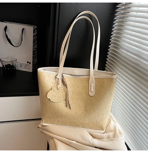 Détail du cabas beige avec cuir gaufré de dessins animés et charm de personnage assorti