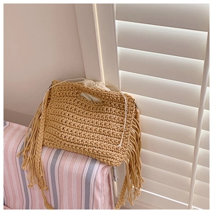 Detail of hand-woven cotton crochet tote bag featuring fringe tassels and drawstring lining