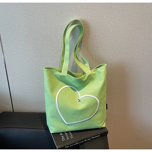 Détail du sac cabas en toile verte avec écusson cœur blanc et clou en métal argenté
