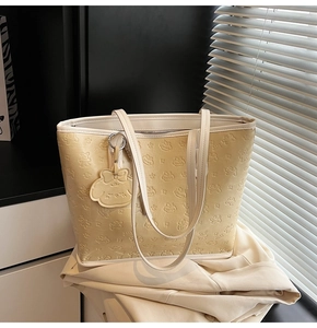 Détail d'un grand sac cabas jaune clair avec motifs gaufrés et breloque assortie