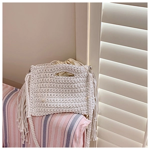 Detail of hand-crocheted white tote bag featuring long fringes and drawstring lining