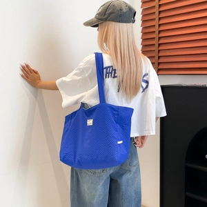 Détail du sac cabas bleu vif en toile texturée avec une petite étiquette blanche