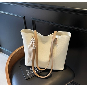 Close-up of cream textured tote bag with silk scarf on a vintage chair setup
