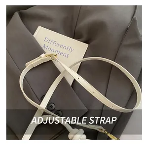 Détail de la bandoulière réglable en cuir blanc avec boucle dorée sur un sac à main