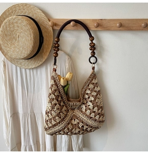 Detail of hand-woven hollow pattern and unique beaded handle on a straw tote bag