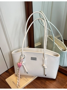 Minimalist white wrinkled leather tote bag with elegant heart charm on a wooden floor
