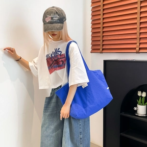 Détail du sac cabas bleu Klein avec texture gaufrée et étiquette blanche minimaliste