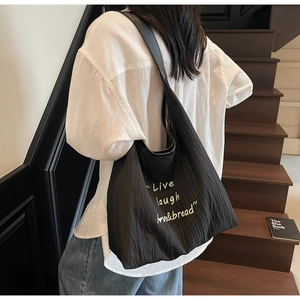 Detail of black pleated tote bag featuring Live Laugh Love print and wide strap