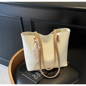 Close-up of beige tote bag with litchi texture, brown handles and heart print silk scarf