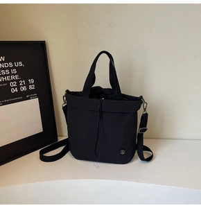 Detail of minimalist black drawstring bucket bag with adjustable nylon shoulder strap