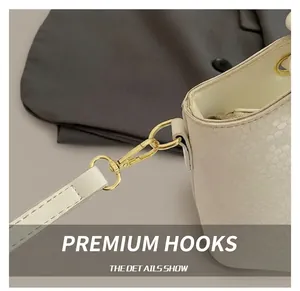 Gros plan détaillé du sac à main en cuir texturé crème avec crochet en métal doré poli