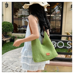 Detail of green crochet woven tote bag featuring a brown leather strap and brand patch