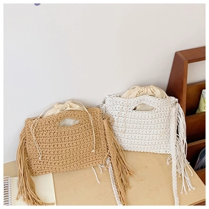 Detail view of woven cotton crochet tote bags with fringe accents in beige and white