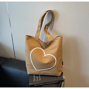 Détail du cœur brodé blanc et du rivet métallique sur le sac en toile marron