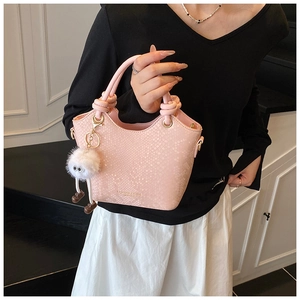 Détail du sac à main rose gaufré serpent avec poignée nouée et breloque en peluche