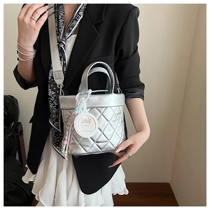 Detail of silver quilted bucket bag with crossbody strap and capybara charm