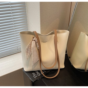 Detailed view of beige tote bag with litchi texture leather and decorative silk scarf