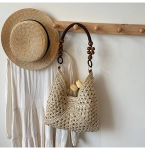 Detail of woven straw tote bag with beaded handle and tulip inside for beach style