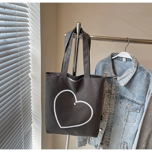 Vue détaillée du sac cabas en toile gris foncé avec cœur blanc sous une lumière douce