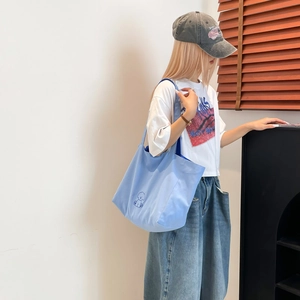 Gros plan d'un sac cabas en toile bleu clair avec broderie chiot porté à l'épaule