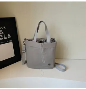 Detail of grey nylon bucket bag with drawstring closure and metal logo plaque