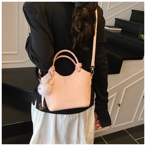 Détail du sac seau rose effet serpent avec garniture dorée et pompon en peluche