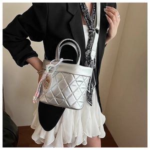 Detail of silver quilted handbag with stylish charms and wide white shoulder strap
