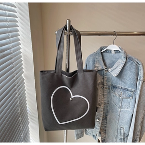 Détail d'un sac en toile gris foncé avec imprimé cœur blanc et cœur métallique argenté