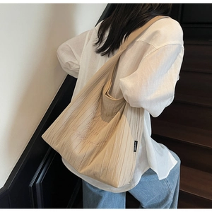 Dettaglio della borsa tote beige a pieghe con ricamo artistico e trama del tessuto