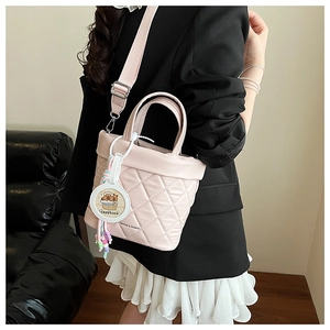 Detail of light pink quilted bucket bag with a cute capybara charm and bead decoration