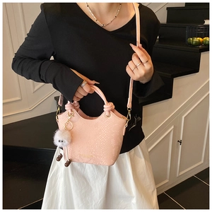 Vue détaillée du sac à main rose motif serpent avec un porte-clé peluche blanc