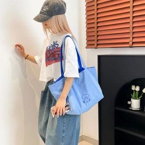 Détail du sac fourre-tout en toile bleu clair montrant la grande capacité et le dessin de chien