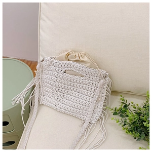 Detail of hand-woven cotton tote bag featuring long tassels and beige drawstring liner