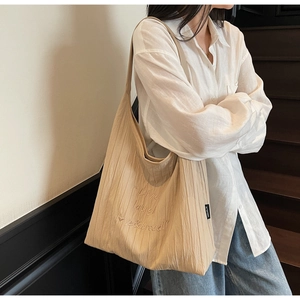 Detail of the pleated beige tote bag with embroidered Live Laugh Love & Bread text
