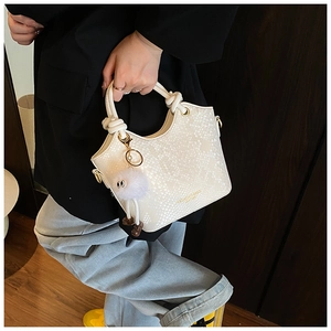 Détail du sac à main blanc motif serpent avec lettrage doré et breloque pelucheuse