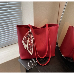 Macro detail of red leather tote bag with elegant floral scarf and fashion branding