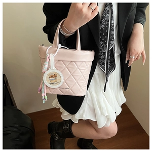 Close-up of pink quilted tote bag with cute capybara charm and brand logo detail