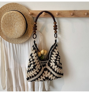 Close-up of woven tote bag with black and white patterns and decorative wooden bead handles