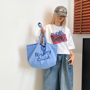 Sac cabas en toile bleu clair avec broderie Rostory Child porté avec style décontracté