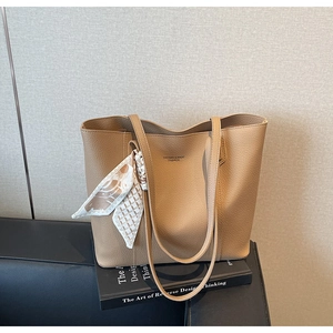 Close-up of khaki faux leather tote bag with grainy texture and decorative silk scarf