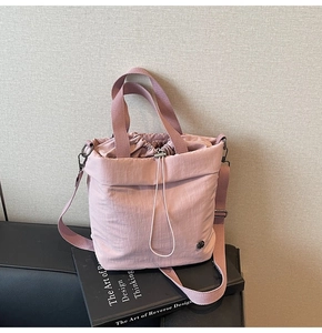Detail of dusty pink drawstring bucket bag featuring durable textured fabric and logo