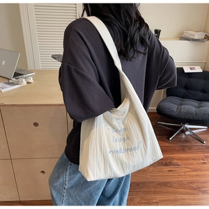 Detail of white pleated tote bag with blue 'Live laugh love&bread' embroidery